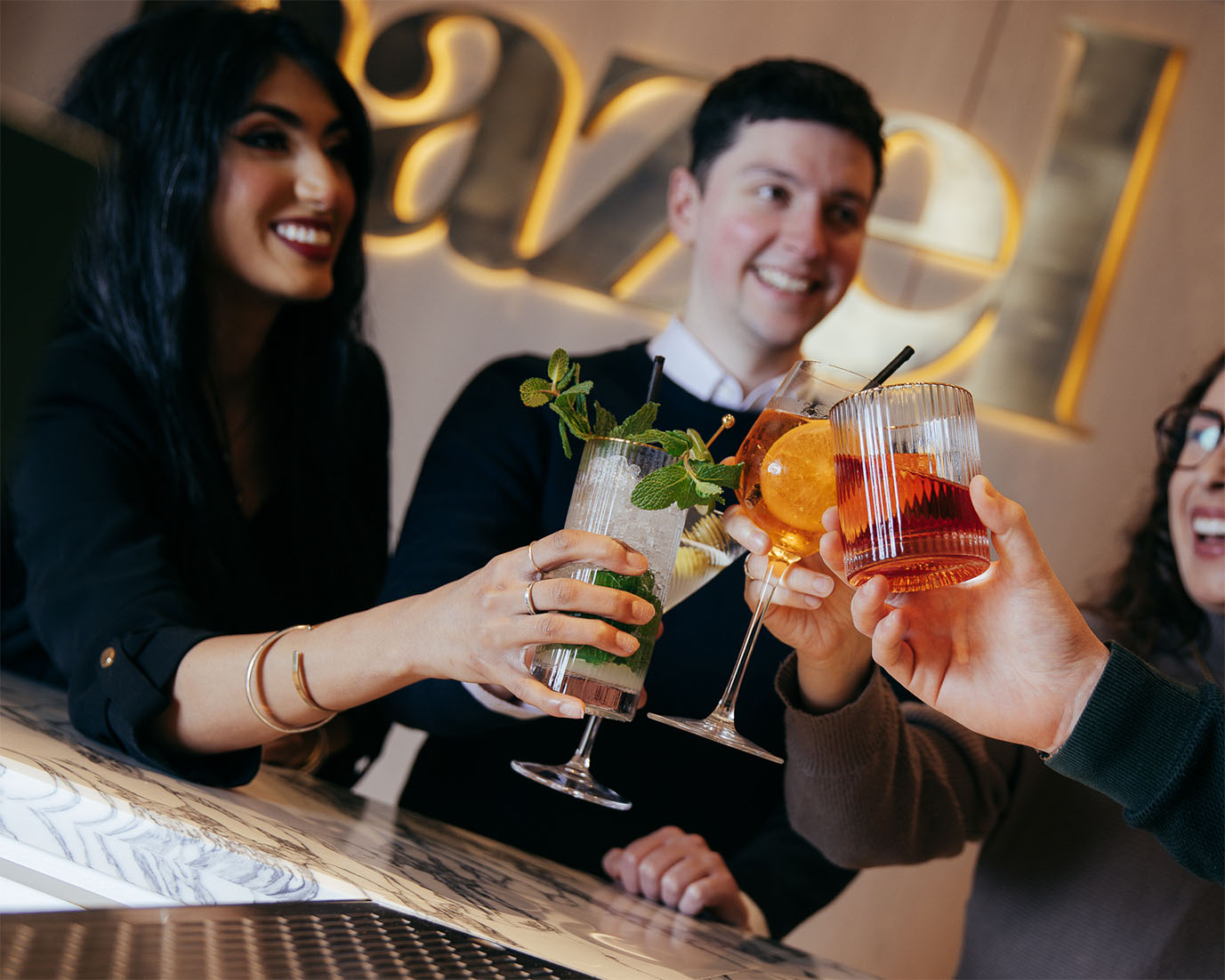 Young happy people toasting cocktails at the bar