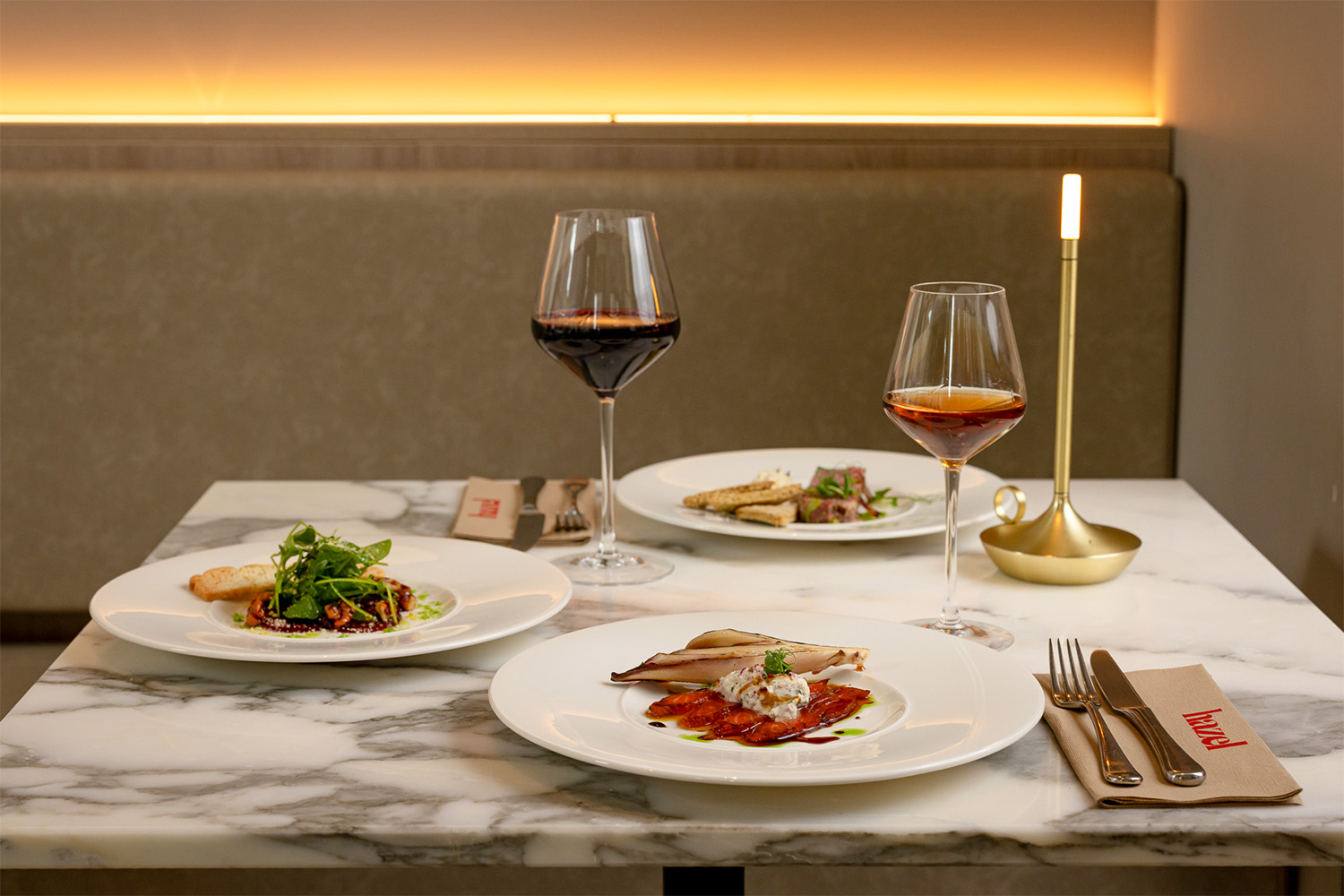 Three plates of food with two glasses of wine